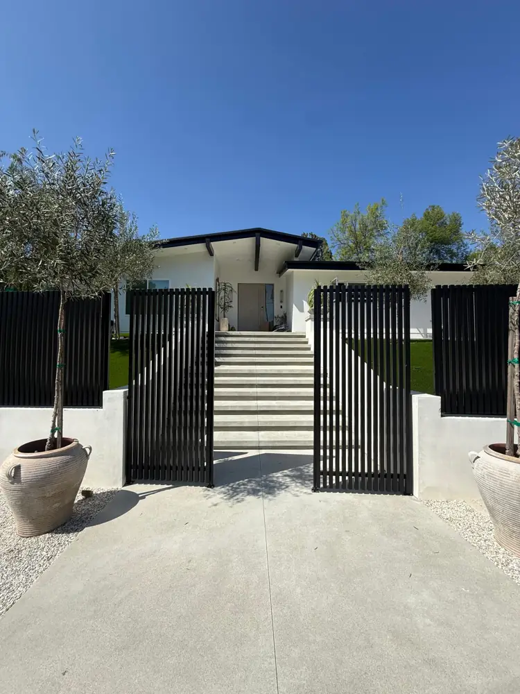 Black slat pedestrian gate and fence at a modern home entry