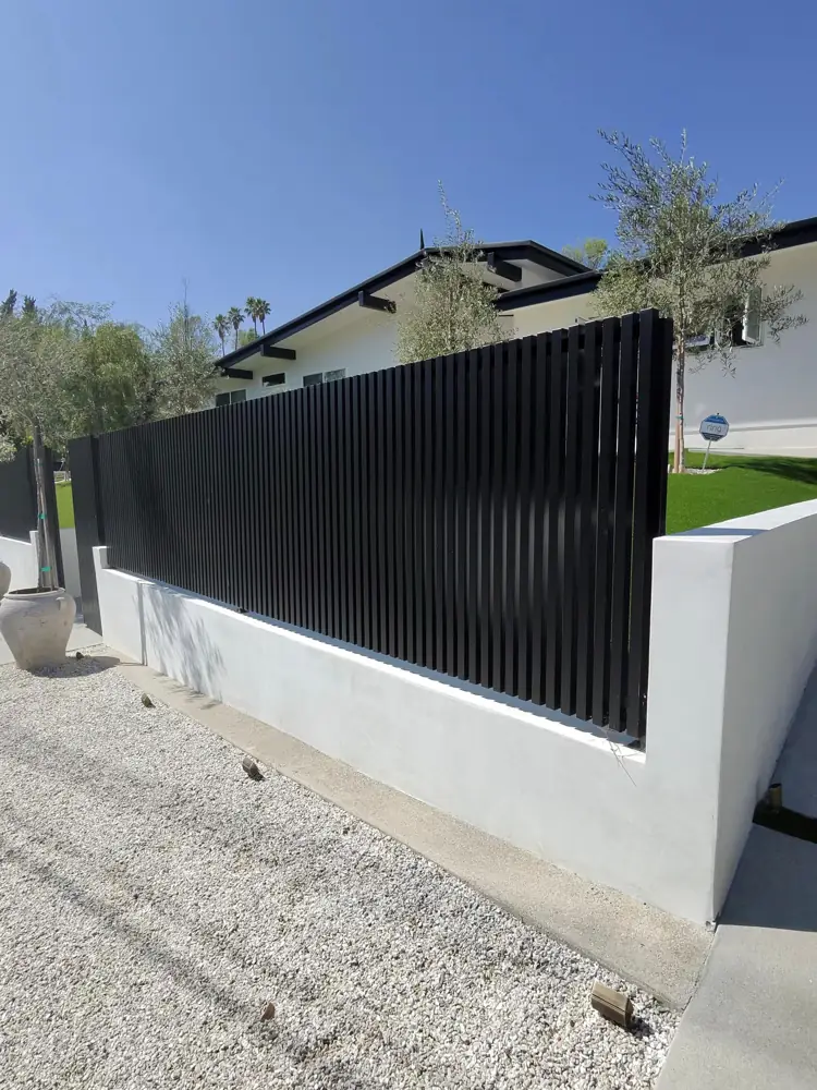 Black vertical-bar fence on a white stucco wall