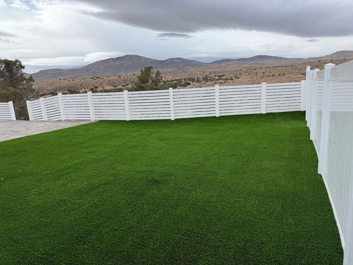 White vinyl fence around a backyard lawn