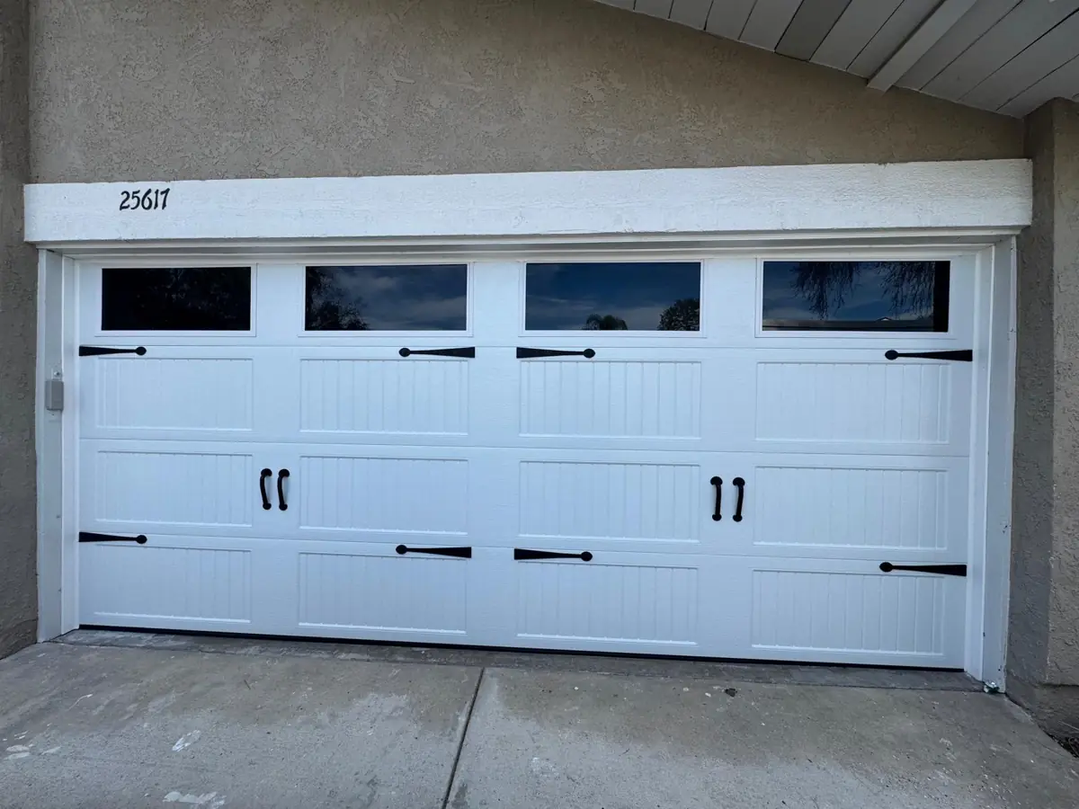 White carriage-house garage door with windows and black hardware