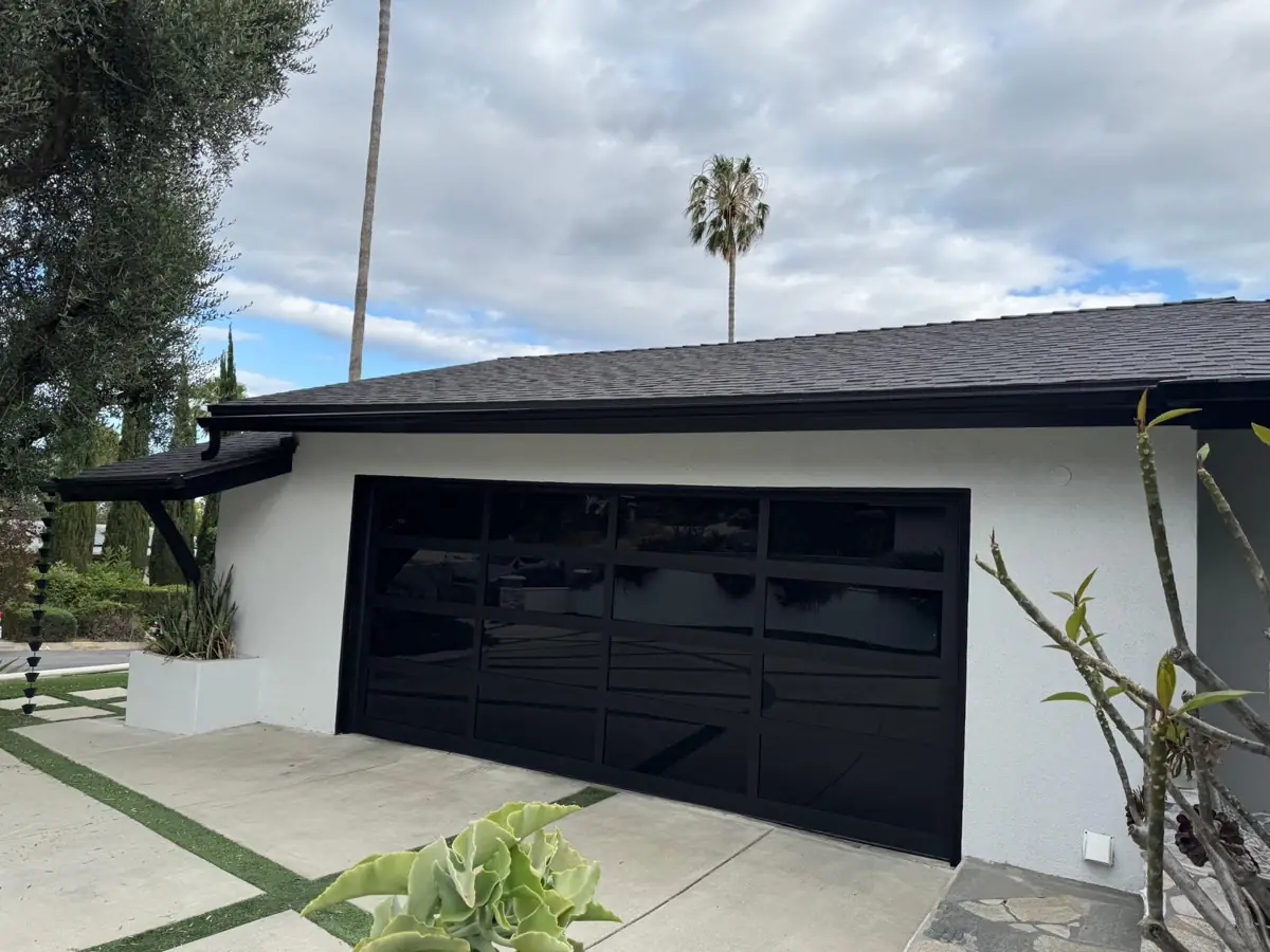 Black full-view garage door on a white house