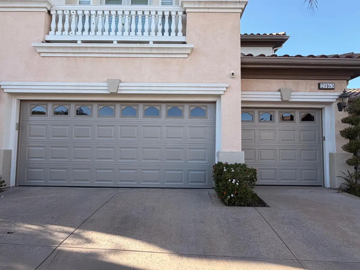 Two white raised-panel garage doors with arched windows