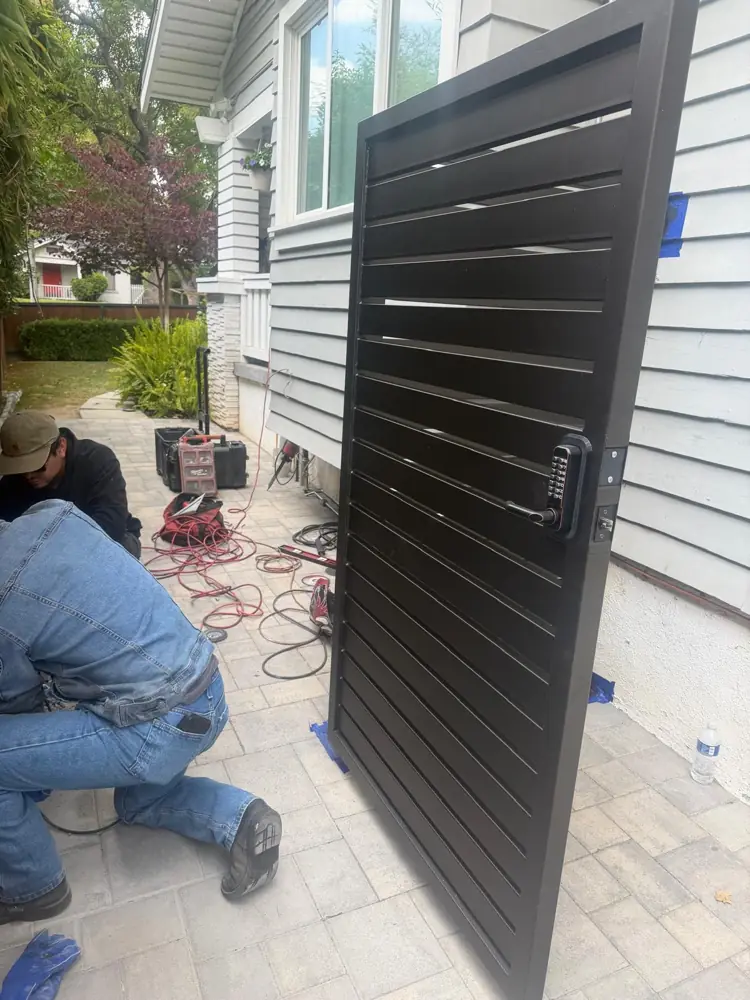 Technician installing a black horizontal-slat side gate