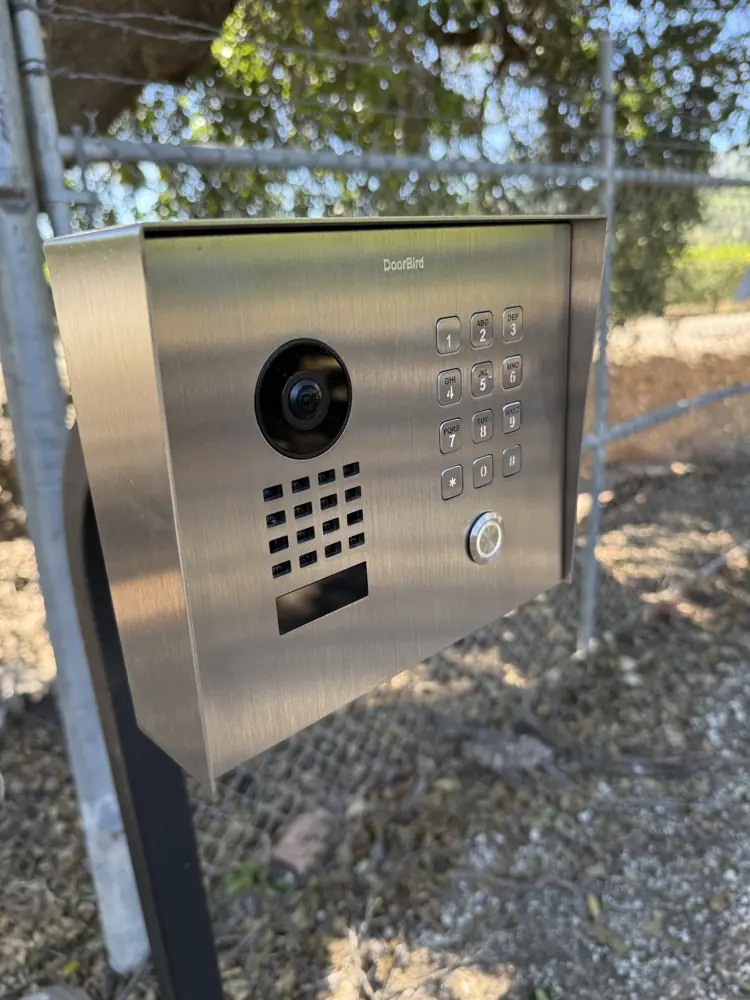 Stainless steel video intercom and keypad at a driveway gate