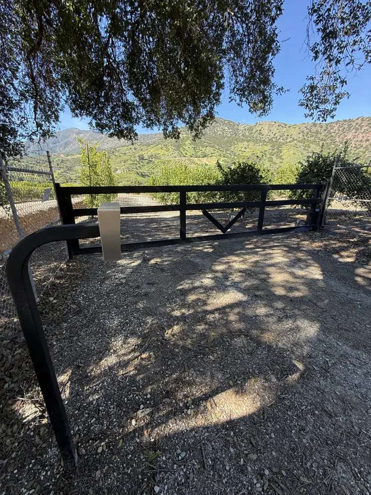 Black ranch-style driveway gate with a view of the hills
