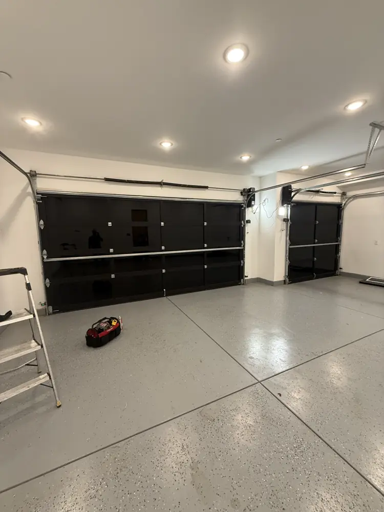 Black glass garage door seen from inside a finished garage