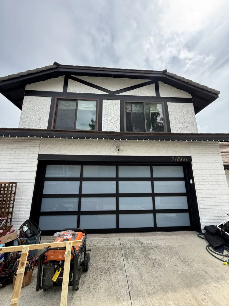 Black full-view glass garage door on a Tudor-style home