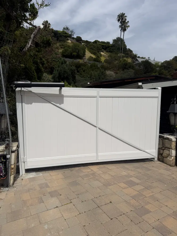 White vinyl driveway gate at a hillside home