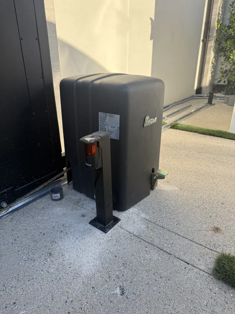 Gate operator motor beside a black gate