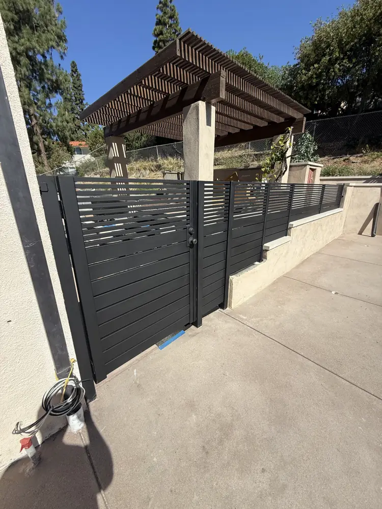 Black slat fence and gate along a sloped driveway