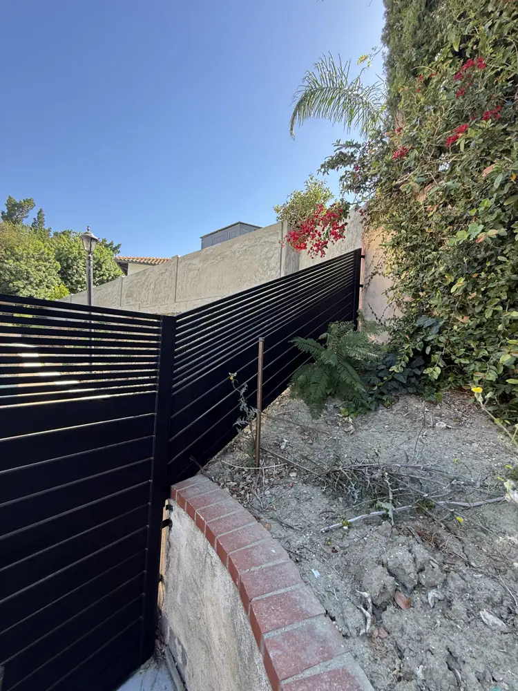 Black slat fence along a garden slope
