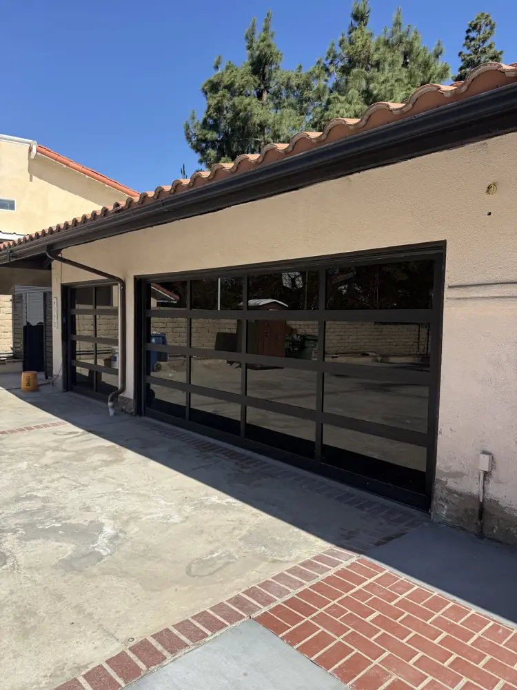 Black full-view glass garage door under a tile roof