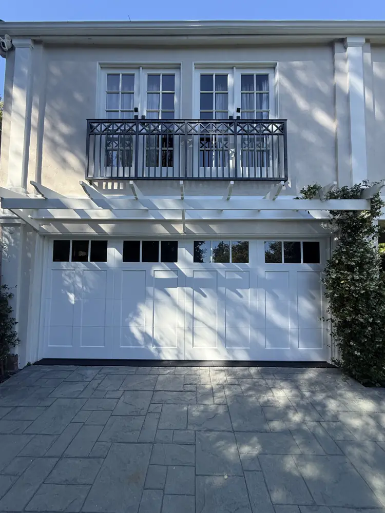 White raised-panel garage door with windows on a classic home