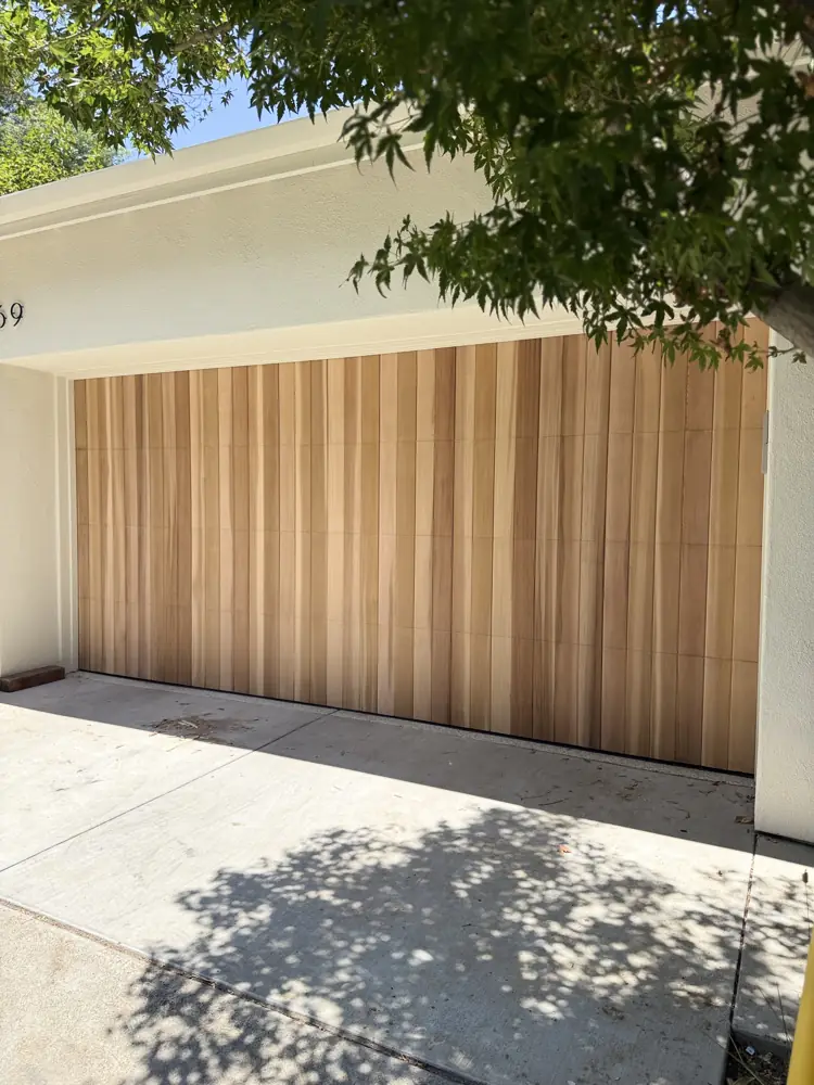 Natural wood plank garage door on a white house