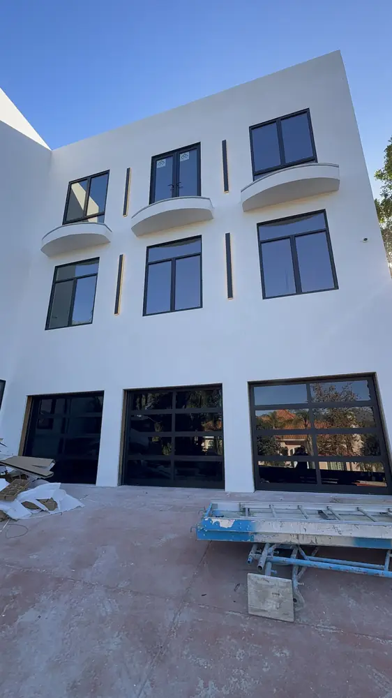 Modern three-story home with glass garage doors