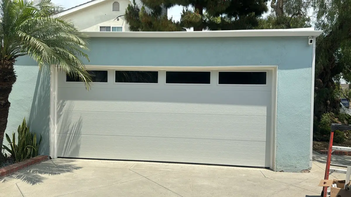 White garage door with windows on a blue house