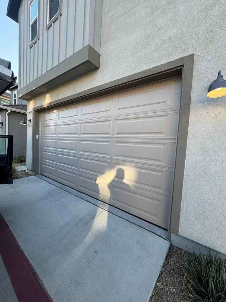 Gray raised-panel garage door beside a modern facade