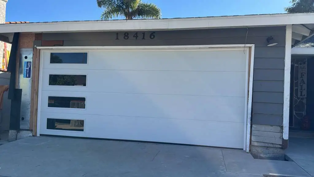 White modern garage door with window column on a gray house