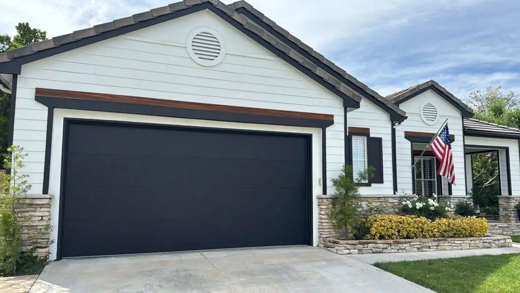 Black flush garage door on a white farmhouse-style home