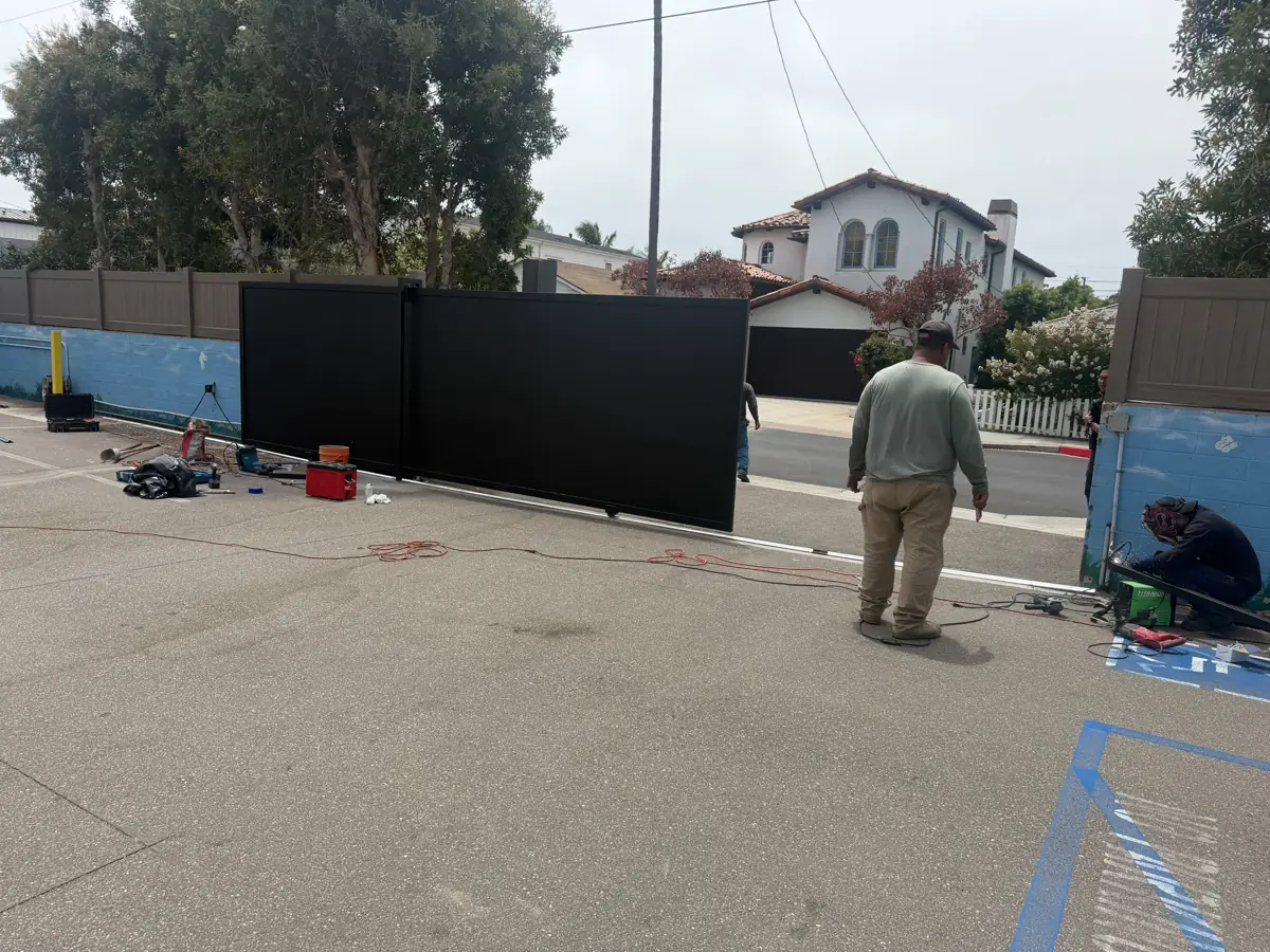 Crew installing a black sliding driveway gate